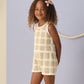 A young girl with curly hair wears the Rylee & Cru Girls' Crochet Tank Set, featuring ruffled trim, standing before a light blue wall with a rope decoration.