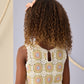 A child with curly hair and a pink bow is seen from behind, wearing the Rylee & Cru Girls' Crochet Tank Set featuring a pastel floral square pattern and delicate ruffled trim.