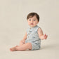 A baby wears the Rylee & Cru Baby Boys' Davis Romper—a sleeveless, light grey outfit with playful sharks print—while sitting on the floor against a neutral background.