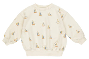The Rylee & Cru Baby Boys' and Boys' Sweatshirt is a beige loose-fit pullover with long sleeves, featuring an all-over sailboats print in muted blue, yellow, and beige tones.