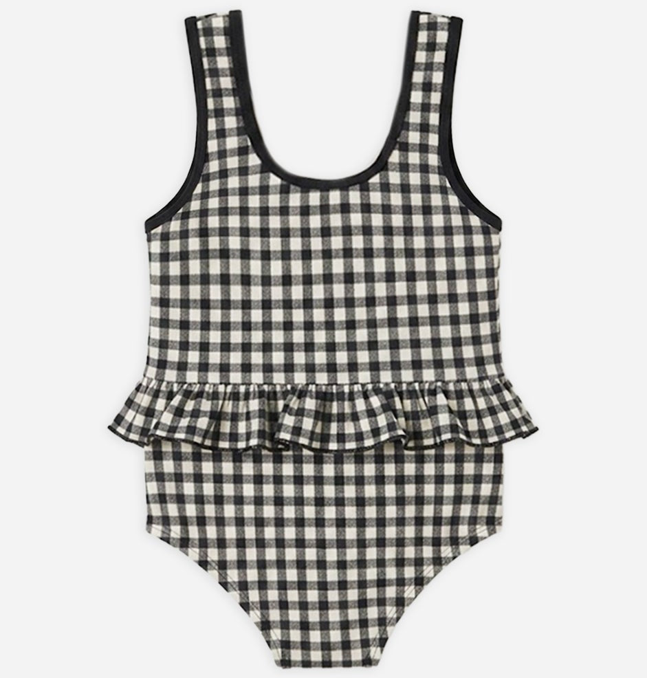 The Rylee & Cru Baby Girls' Skirted One-Piece features a black and white checkered pattern, a scoop neckline, UPF 50+ sun protection, and an adorable ruffled waistline detail. Shown laid flat on a white background—it's the perfect swimsuit for your little one's next pool day.