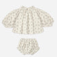 The Baby Girls’ Quincy Set by Rylee & Cru includes a long-sleeve top and coordinating bloomer made from lightweight fabric, showcasing a delightful gray leaf print on a crisp white background.