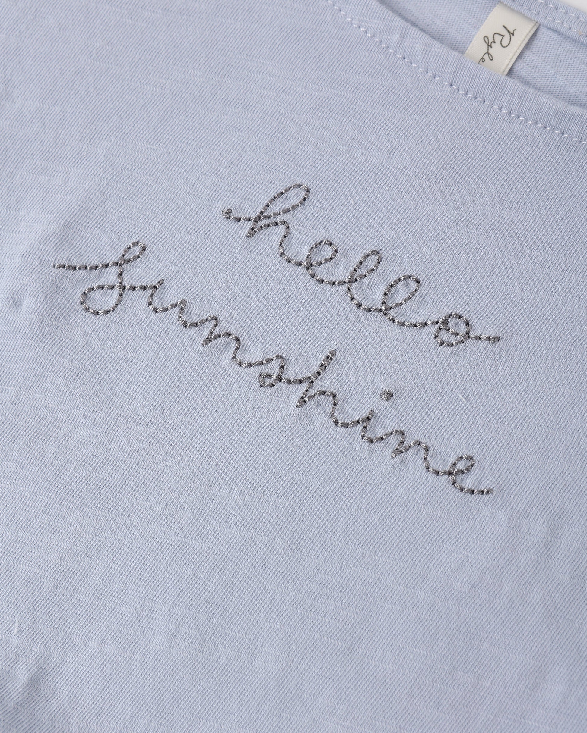 The Rylee & Cru Girls' Cropped Cinch Tee features a light blue color, cinched fit, and "hello sunshine" embroidered in gray cursive for a relaxed, cheerful look.
