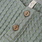 Close-up of Rylee & Cru's Baby Boys' Beau Romper in textured sea green, with two wooden buttons and a white collar tag—a stylish summer outfit.
