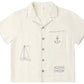 The Rylee & Cru Boys' Lapel Collar Shirt is a cream short-sleeve button-up with stitched sailboat, anchor, and fish designs on the front.