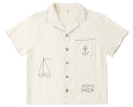 The Rylee & Cru Boys' Lapel Collar Shirt is a cream short-sleeve button-up with stitched sailboat, anchor, and fish designs on the front.