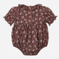 The Rylee & Cru Baby Girls’ Liv Romper is a vintage-inspired brown bubble romper featuring short sleeves, a scalloped ruffled collar, and a white floral pattern. Designed with front buttons and elastic leg openings for comfort, the garment is displayed laid flat on a white background.