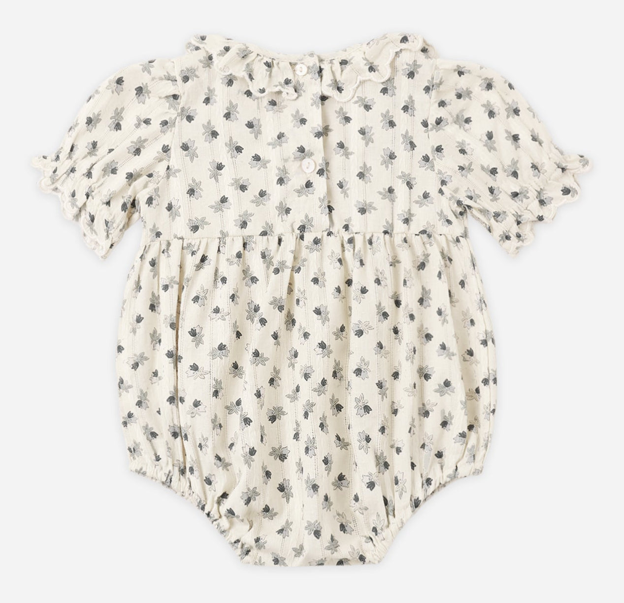 The Rylee & Cru Baby Girls’ Liv Romper is a vintage-inspired bubble romper featuring short puffed sleeves, a ruffled scalloped collar, and a black floral pattern on white fabric, with three buttons visible on the back.
