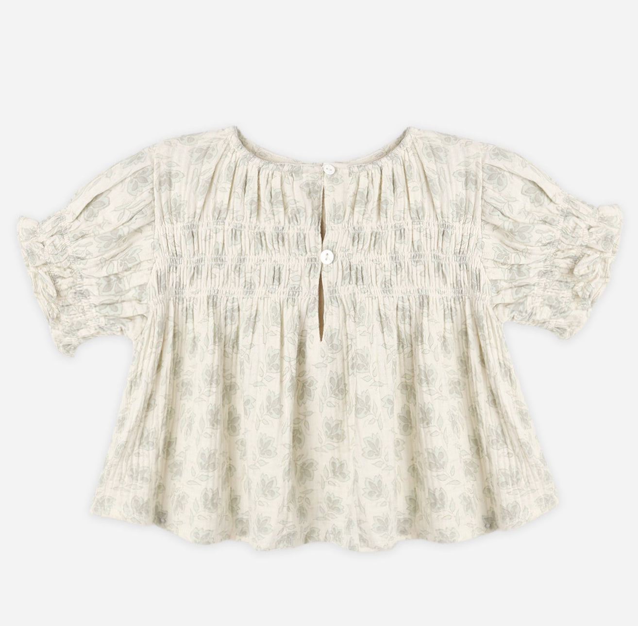 Light-colored, short-sleeved Girls’ Colette Top by Rylee & Cru, featuring a charming floral pattern, smocked detailing at the chest for a flattering fit, ruffled cuffs, and two buttons at the front neckline, displayed on a plain background.