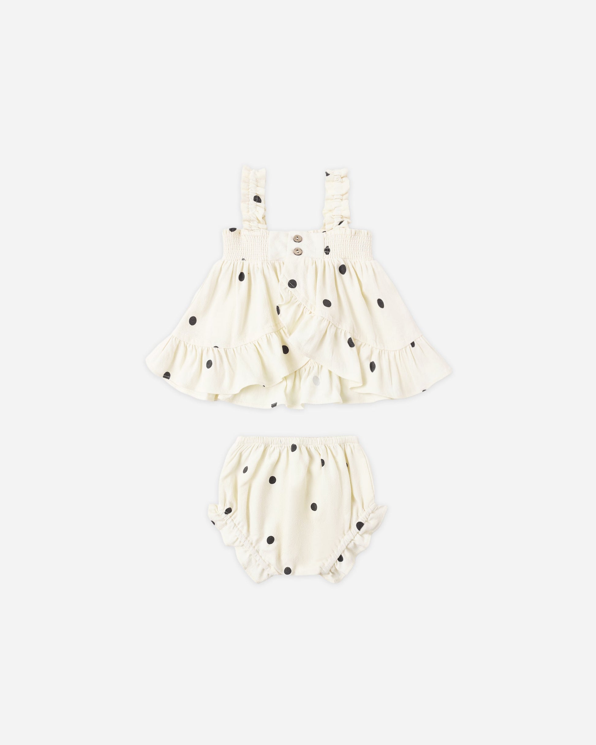 The Rylee & Cru Baby Girls' Lala Set is a two-piece white outfit with black polka dots, featuring a ruffled sleeveless top with smocked detail and matching flutter bloomers.