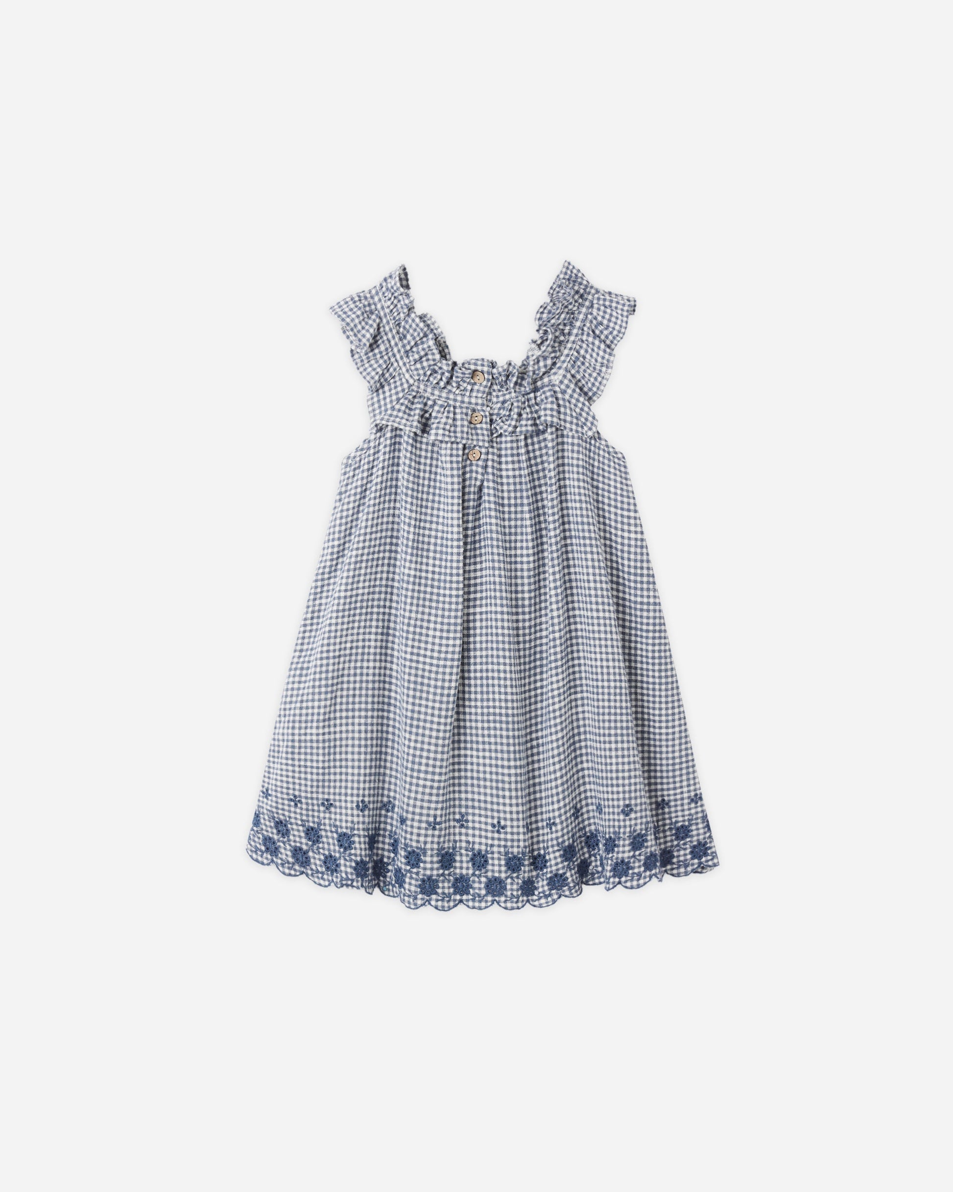 The Girls' Lennon Dress by Rylee & Cru is a sleeveless blue and white gingham mini dress with a ruffled neckline and blue floral embroidery along the scalloped eyelet hem.
