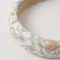 Close-up of the Rylee & Cru Girls' Padded Headband, featuring a pastel bloom pattern with orange, blue, and yellow flowers on a white background—an ideal summer accessory.