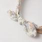 A close-up of the Rylee & Cru Baby Bow Headband, featuring a floral pattern, knotted design, and a scrunchy elastic band, shown against a plain white background.