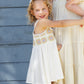 A young girl wearing the Rylee & Cru Girls' Crochet Sundress smiles and points beside an adult in cream, both showcasing vintage charm against a blue wall.