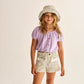 A young girl stands against a plain background, wearing the Cozmo Girls' Judy Terry Top in a cropped silhouette with a boat neckline, paired with a floral bucket hat and matching floral shorts featuring pockets.
