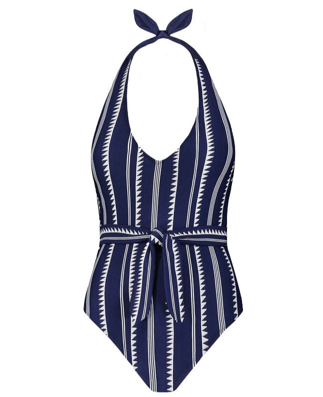 The Lemlem Lidya One Piece, offered by the brand Lemlem, is a navy blue one-piece swimsuit adorned with white zigzag and vertical stripes. It features a halter neck and front tie design. Responsibly made and Oeko-Tex certified, it combines style with sustainability.