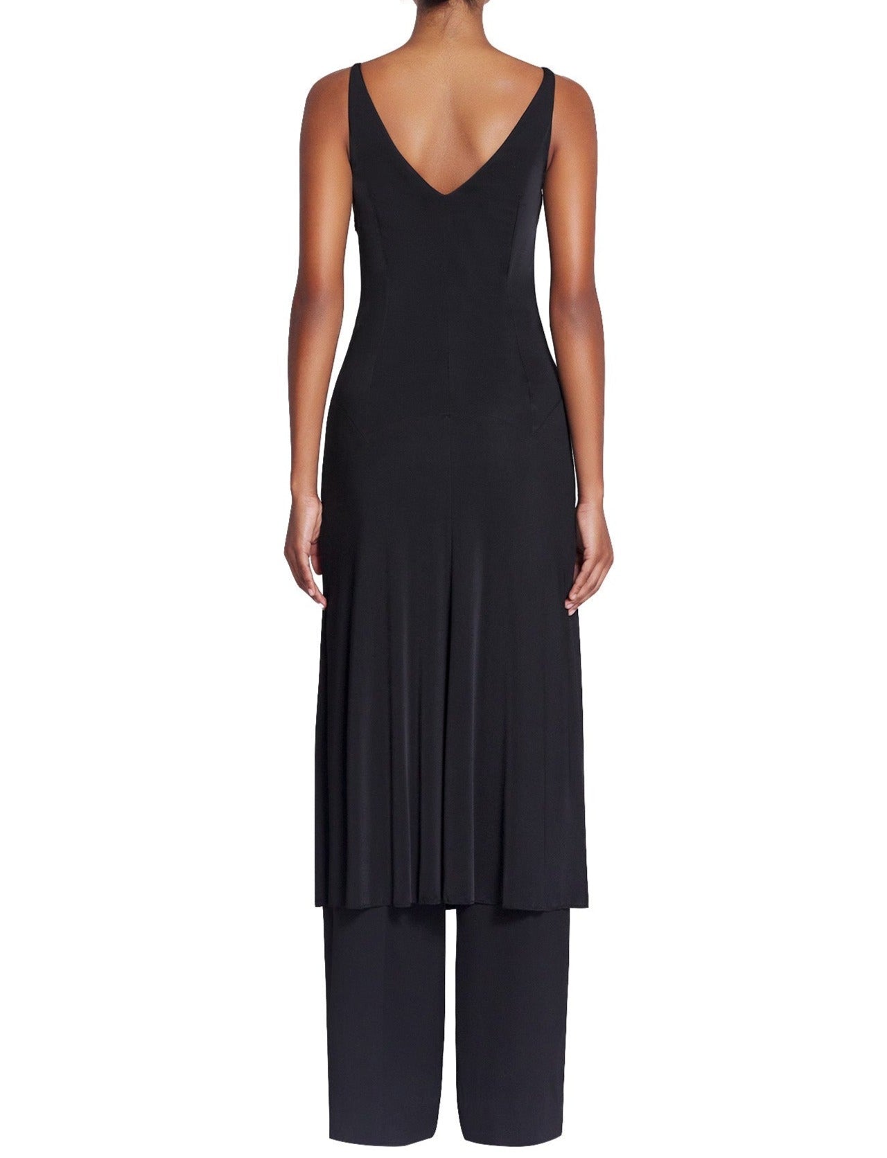 Rear view of a woman wearing a black sleeveless Lanvin Sleeveless A-Line Midi Dress with a v-shaped back, layered over black pants.