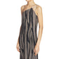 A woman wears the Lanvin Asymmetrical Cascade-Effect Dress, a sleeveless, pleated design with a chain strap and asymmetric neckline, featuring a black and beige zebra print.
