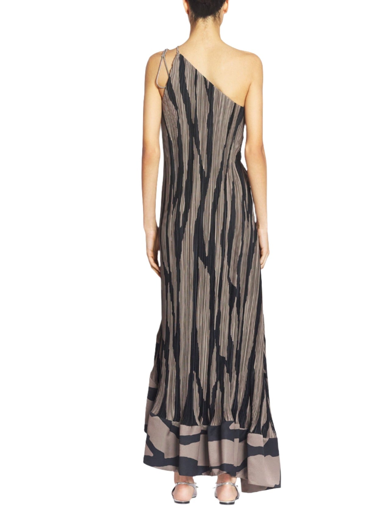 A person wearing the Lanvin Asymmetrical Cascade-Effect Dress, featuring a one-shoulder design with an asymmetrical pleated silhouette and a vertical black and beige pattern, accented by a single metal chain strap, stands facing away.