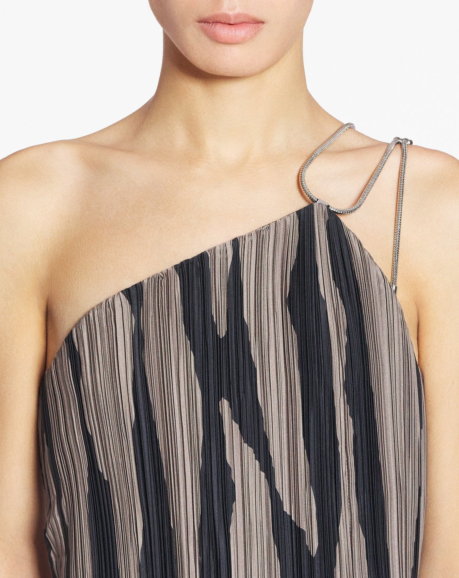 Dressed in the Lanvin Asymmetrical Cascade-Effect Dress, featuring black and brown vertical stripes and a single metal chain strap, adds a touch of elegance.