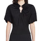 A woman wearing the Lanvin Summer Top with Eyelet Detail, featuring ruffled short sleeves, soft black viscose jersey, and a central metallic keyhole cutout at the neckline.