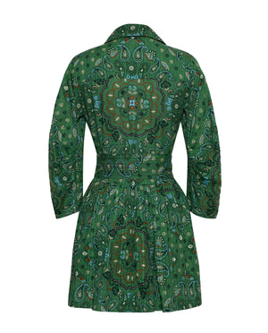 The Raya Mini Dress by Cara Cara showcases a green long-sleeve silhouette adorned with a mandala and paisley print, seen from the back. It features a fitted waist with an elegant sash accent and a flared skirt.