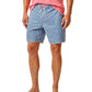 A person wearing a pink shirt, Johnnie-O Red Fin Blue Fin Swim Shorts featuring fun prints, and brown sandals.