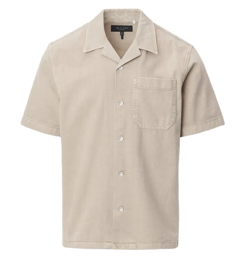 The Rag & Bone Resort Denim Shirt is a beige, short-sleeve camp shirt with a chest pocket, collar, and white buttons, crafted from featherweight denim and shown against a plain white background.