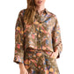 A woman wears the Hunter Bell NYC Clarke Shirt, a modern brown collared long-sleeve top, paired with matching pants in a colorful floral pattern.