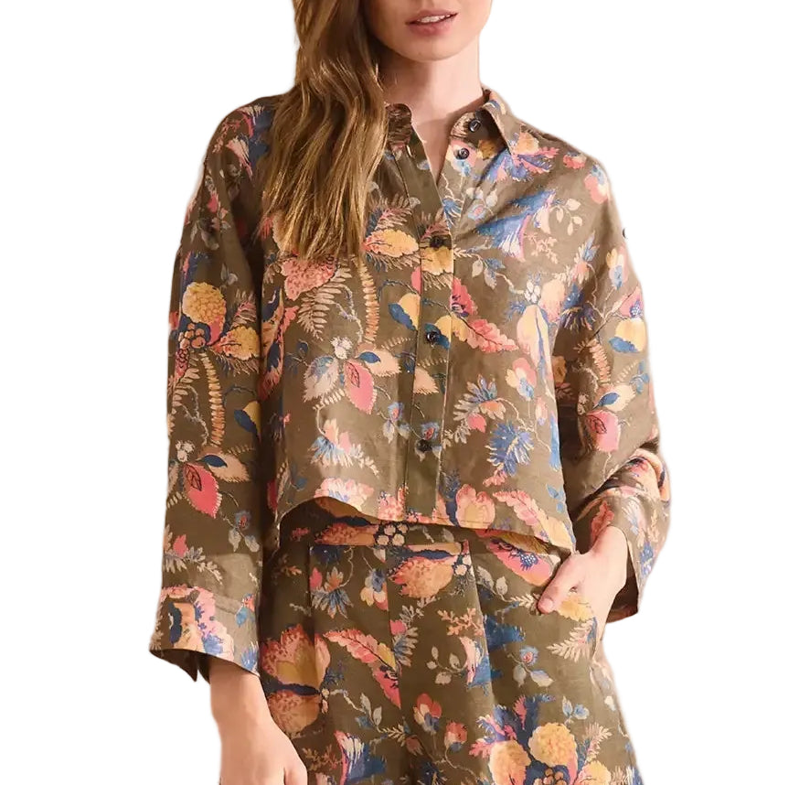 A woman wears the Hunter Bell NYC Clarke Shirt, a modern brown collared long-sleeve top, paired with matching pants in a colorful floral pattern.