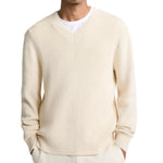 A man wearing the vince Spring Rib Longsleeve V Neck sweater in cream over a white T-shirt, with his hands in his pockets.