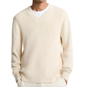 A man wearing the vince Spring Rib Longsleeve V Neck sweater in cream over a white T-shirt, with his hands in his pockets.