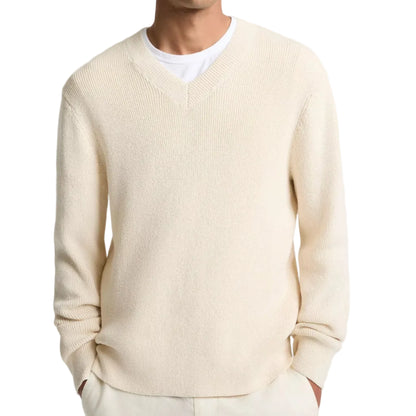 A man wearing the vince Spring Rib Longsleeve V Neck sweater in cream over a white T-shirt, with his hands in his pockets.