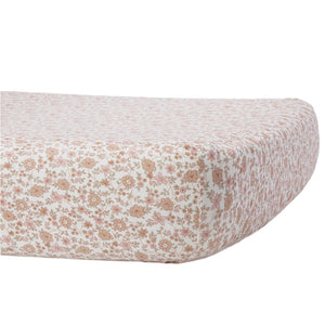 A close-up of the Quincy Mae Bamboo Crib Sheet shows its small pink and beige floral pattern on a white background covering a mattress or cushion.