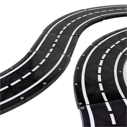 Close-up of a black plastic toy race track with white lane markings and visible screws, designed for modular builds. Inspired by the Magnatiles XTRAS: Roads 12-Piece Set.