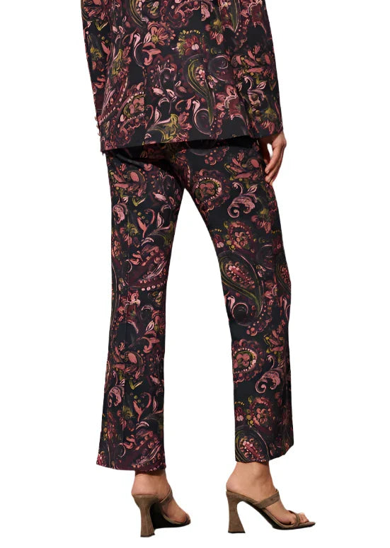 A person wearing the Figue Sioban Pant, featuring a matching polyester paisley floral print suit, viewed from the back, paired with open-toe high-heeled sandals.