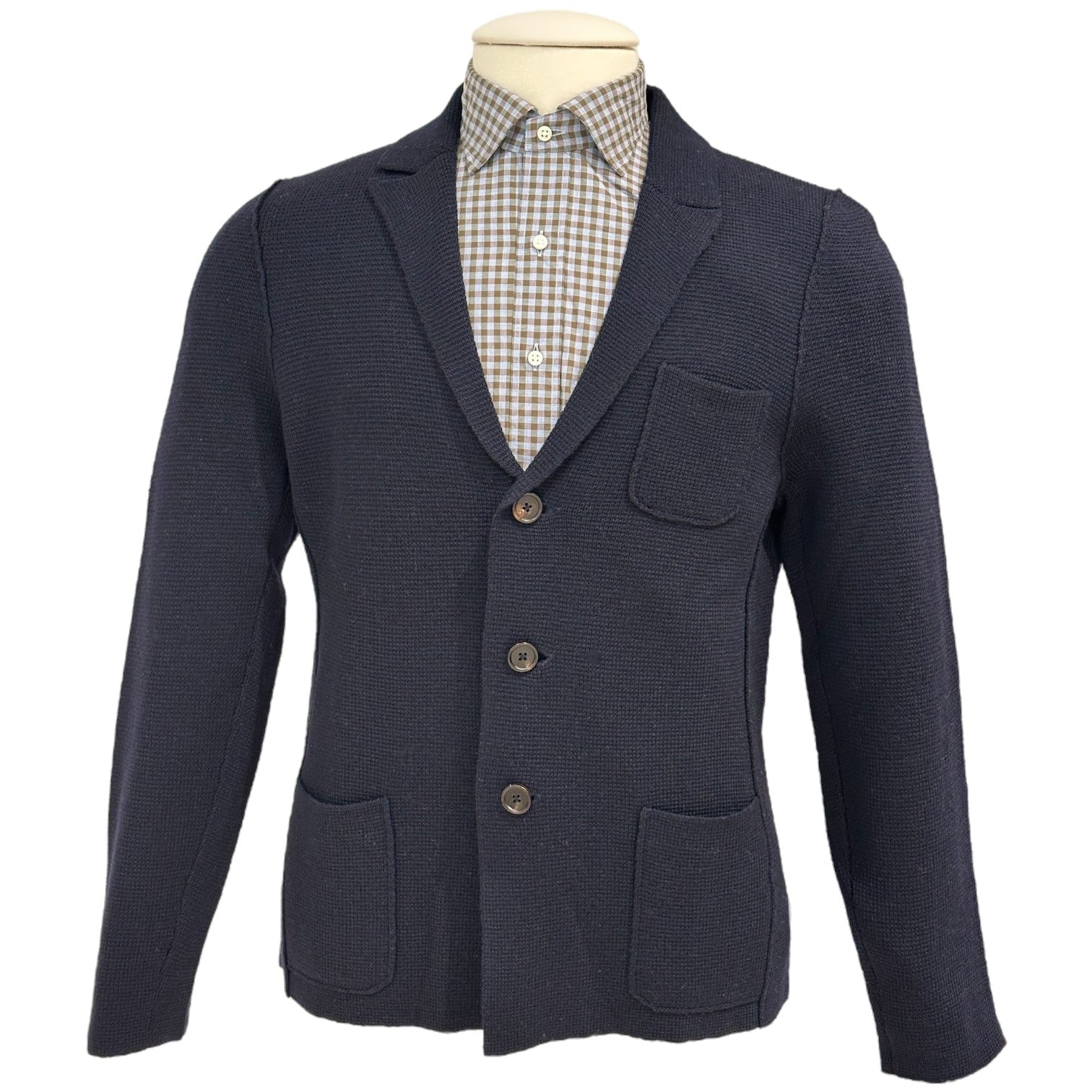 The Alan Paine Rudston Cardigan features a tailored fit in navy blue with a textured finish, three buttons, patch pockets, and a notched lapel, displayed over a buttoned checkered shirt on a mannequin.