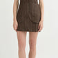 A woman wears the POSSE Alice Pinstripe Skirt, a brown pinstripe mini skirt with large pockets and front buttons, styled with flat sandals, standing against a plain white background.