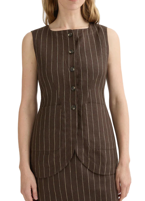 A woman wears the Emma Pinstripe Vest by POSSE—a sleeveless, brown pinstripe vest with front buttons, two large front pockets, and a classic silhouette, crafted from premium linen.
