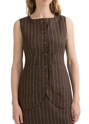 A woman wears the Emma Pinstripe Vest by POSSE—a sleeveless, brown pinstripe vest with front buttons, two large front pockets, and a classic silhouette, crafted from premium linen.