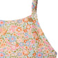 Close-up of the Bonpoint Girls' Emna Swimsuit One-Piece in Liberty Print, featuring a floral pattern in pink, blue, orange, and green with a thin shoulder strap and a small round button at the top.