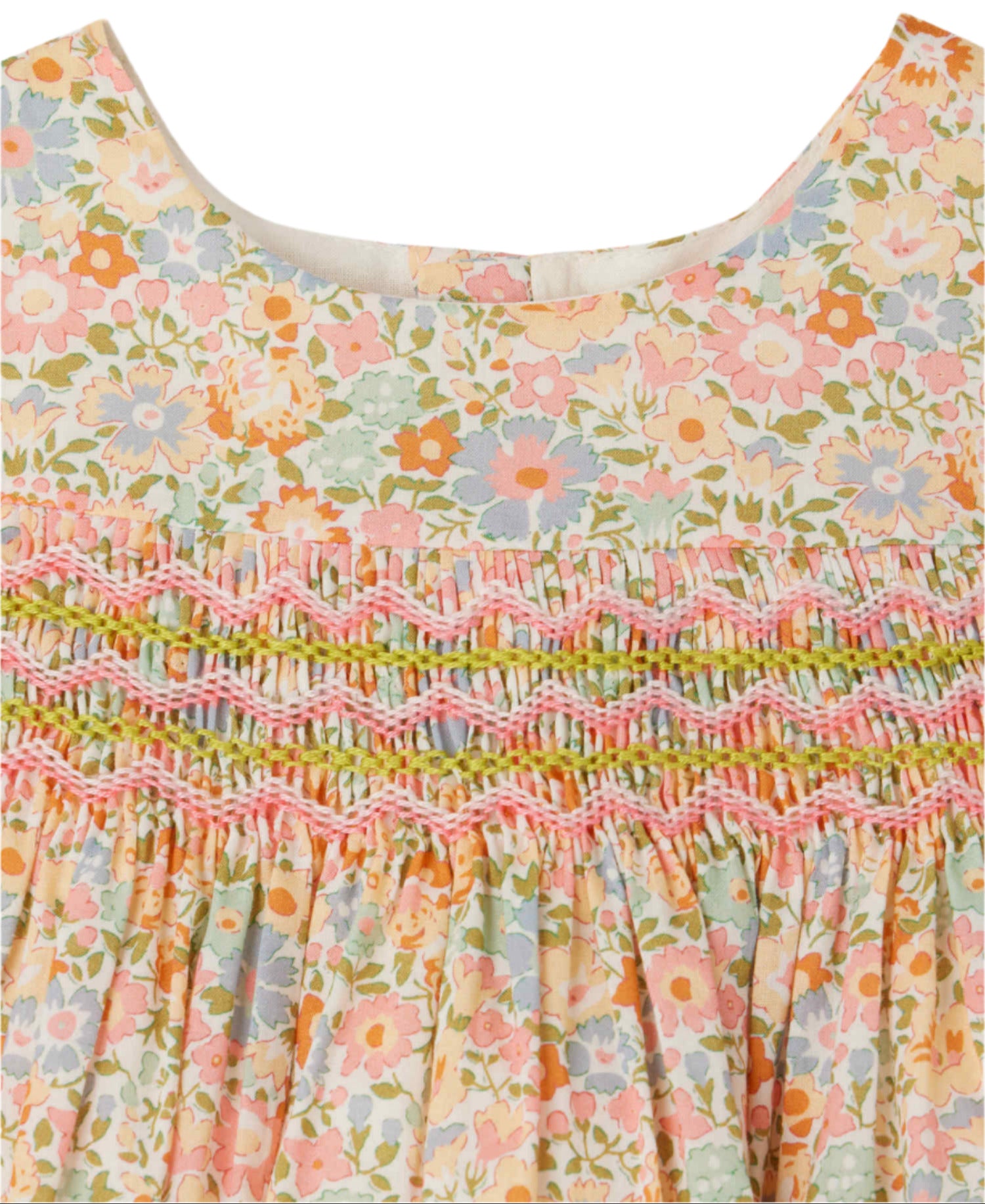 Close-up of the Bonpoint Baby Girls' and Girls' Maruska Smocked Dress made with Liberty fabric, featuring pastel floral patterns and detailed pink and green hand-embroidered smocking across the chest.