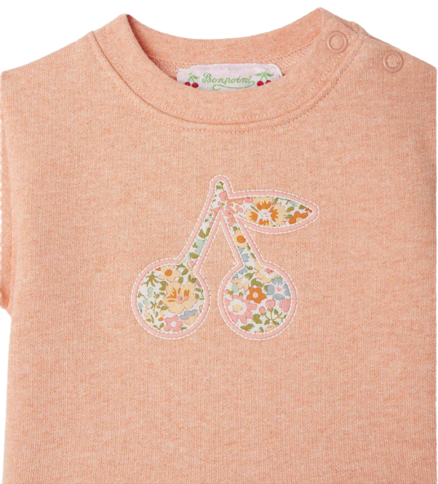 The Bonpoint Clelie t-shirt for baby girls features a cherry motif in Liberty Fabrics on organic cotton, with a peach hue and two shoulder buttons for easy dressing.