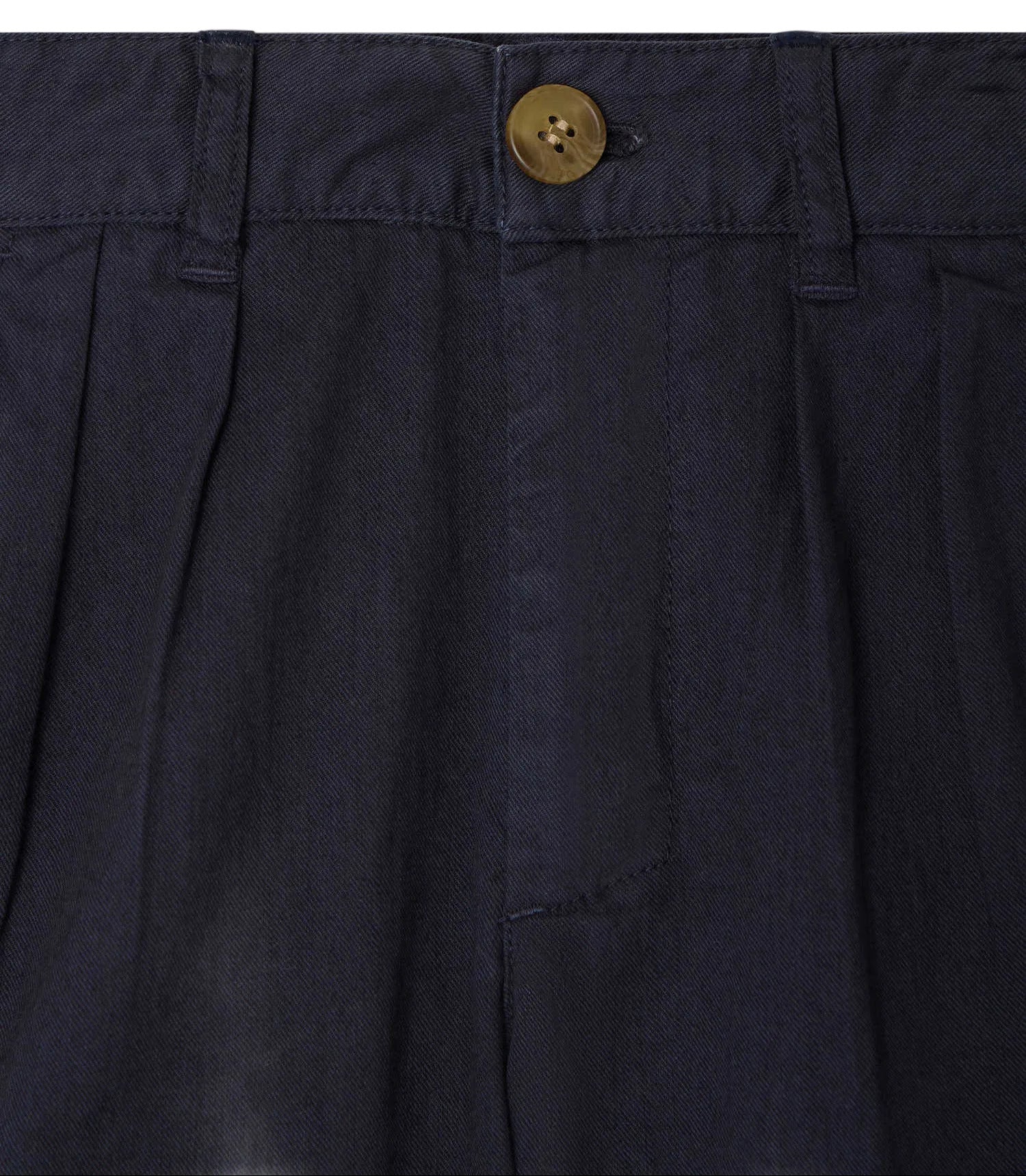 Close-up of the waistband and button closure of Bonpoint Boys' Charles Chino Bermuda Shorts with Pleats, in dark navy organic cotton, featuring pleats and belt loops.