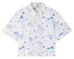The Boys' Erian Shirt by Bonpoint features short sleeves and a button-up front, made from soft organic cotton in white with blue island-themed illustrations of palm trees, sailboats, and waves.