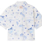 The Boys' Erian Shirt by Bonpoint is a short-sleeved, button-up shirt for boys, made from organic cotton with a white base and blue island-inspired prints featuring palm trees, sailboats, water, and handwritten phrases.