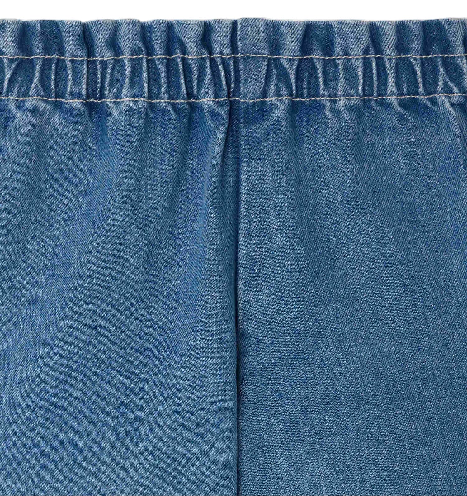 Close-up of blue denim fabric with an elastic waist and vertical center seam, featured in Bonpoint Girls' Milly Shorts.