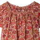 Close-up of the Bonpoint Girls' Goldia blouse in Liberty Fabric, featuring a floral print on a light pink background with a smocked off-the-shoulder neckline, crafted from soft organic cotton for comfort and style.