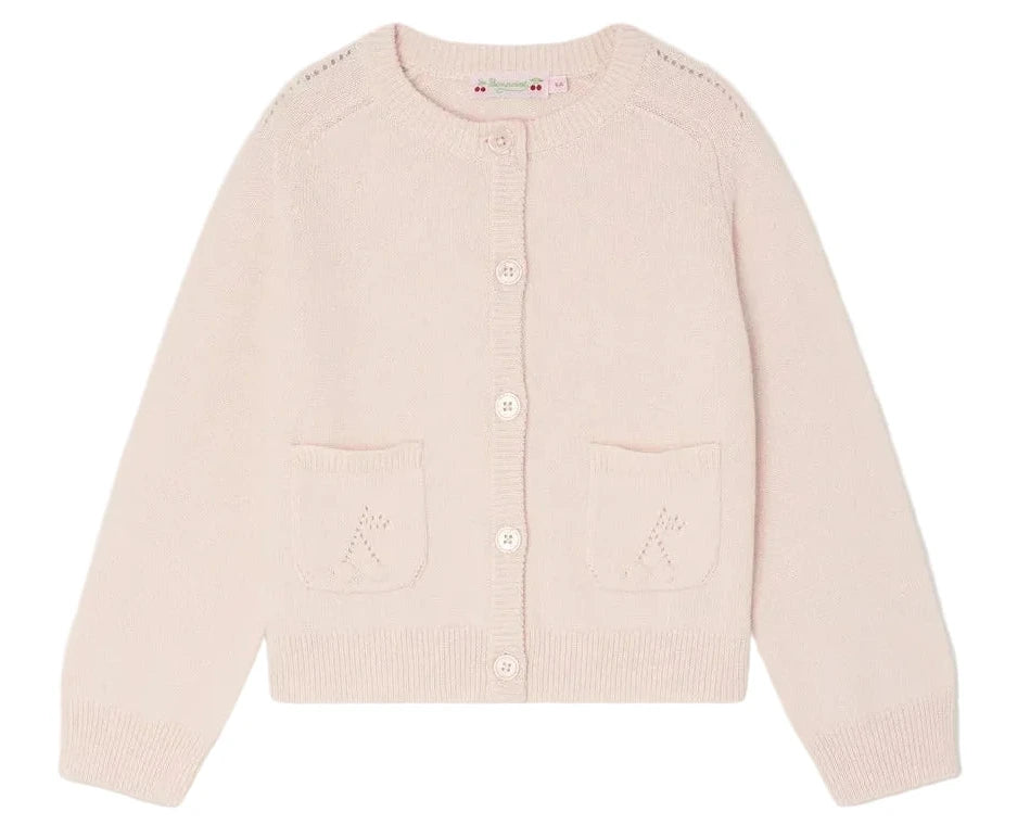 The Bonpoint Girls' Elisea Round Neck Cardigan in Organic Cotton is light pink with long sleeves, front white buttons, and two small front pockets.
