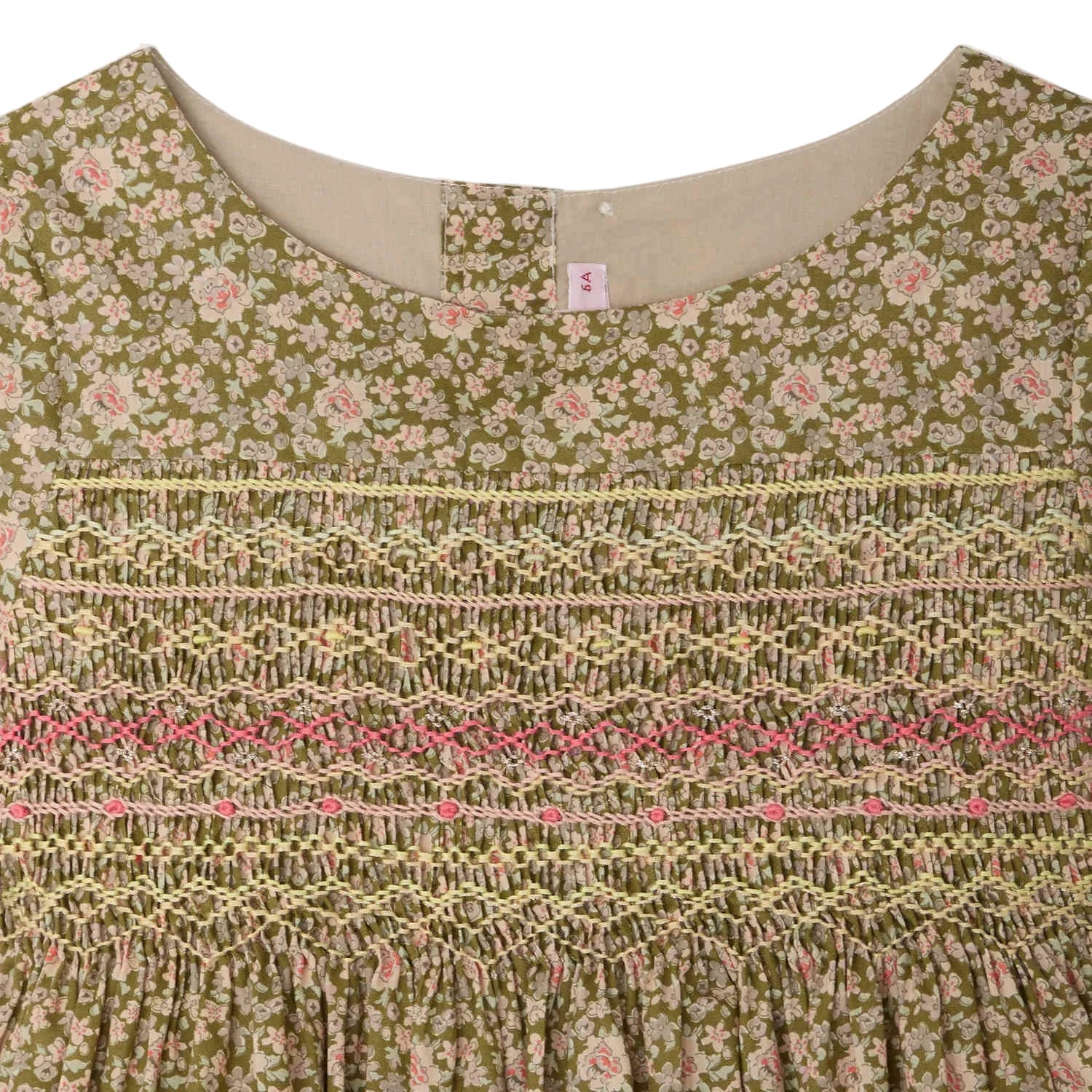 Close-up of the Bonpoint Girls' Duchesse Smocked Dress in Liberty fabric, showcasing hand-embroidered smocking with intricate yellow and pink embroidery across the chest.